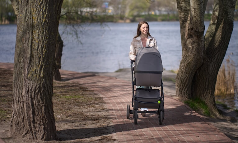 maminka s kočárkem na procházce v parku