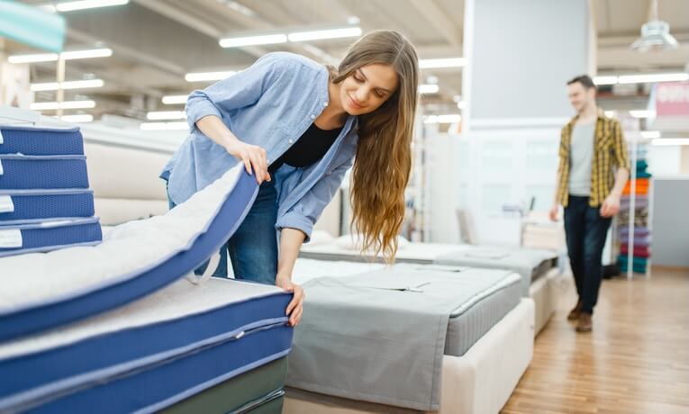 mladá žena si prohlíží matrace v obchodě