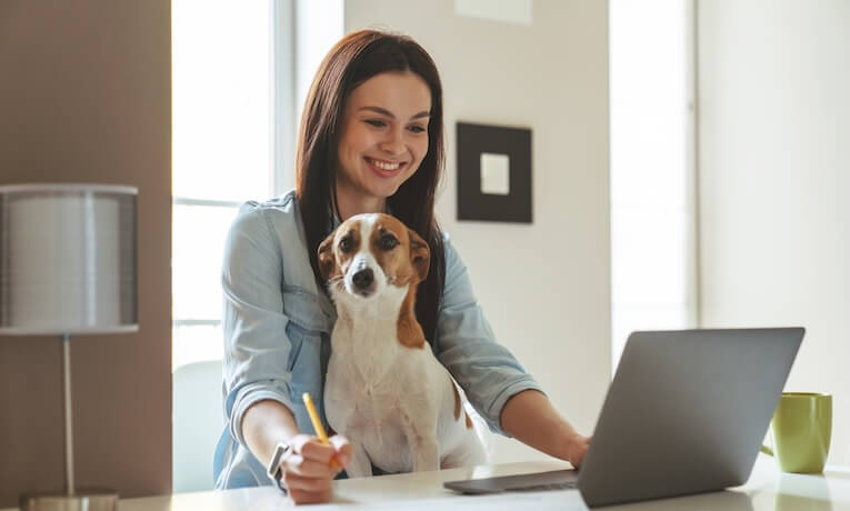 žena pracující na notebooku s pejskem na klíně