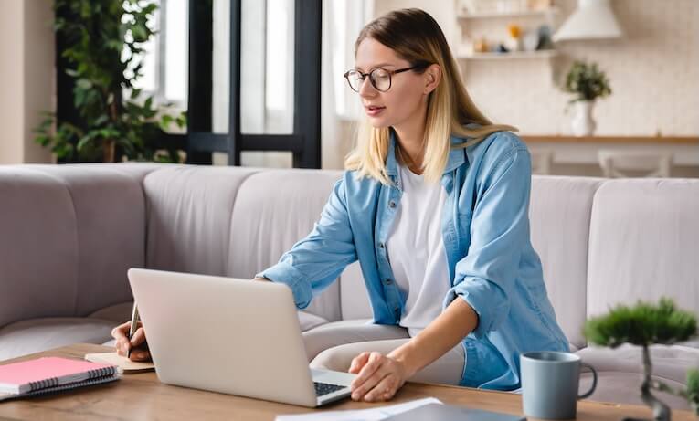 žena pracující na notebooku doma na pohovce