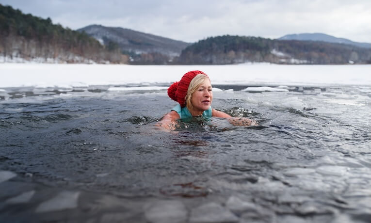 žena středního věku se otužuje v zamrzlém jezeře