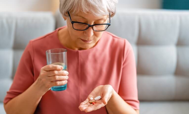 žena v zralém věku se chystá vypít několik pilulek