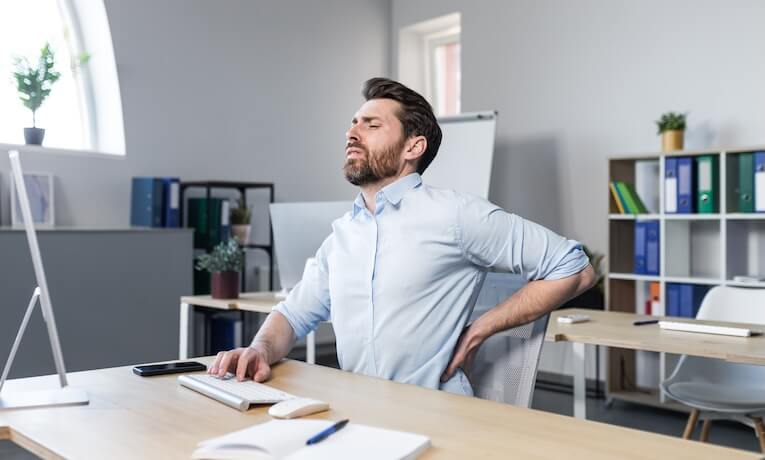 muž pracující na počítači má bolesti zad