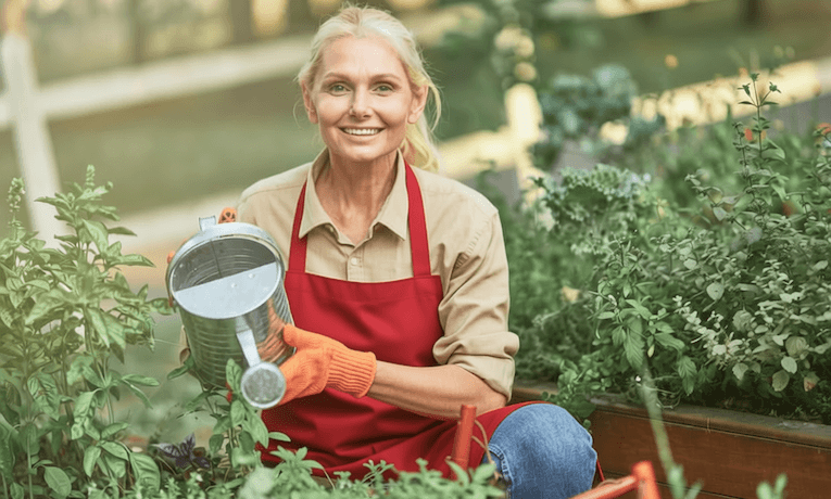 žena v zralém věku zalévá rostliny na zahradě