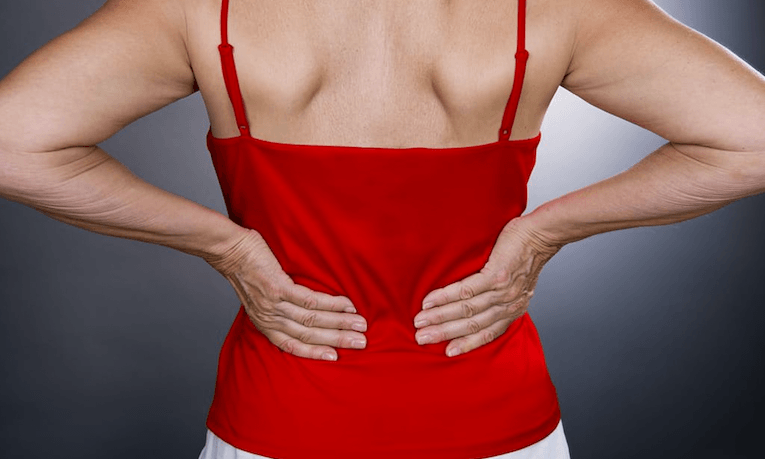 ženská záda v červeném tílku s rukama položenými na bedrech