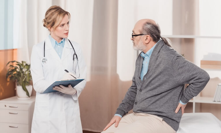 starší pacient konzultuje s lékařkou bolest v oblasti kříže