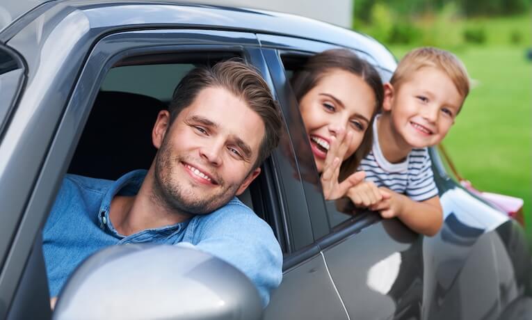 mladá tříčlenná rodina vykukuje z oken auta