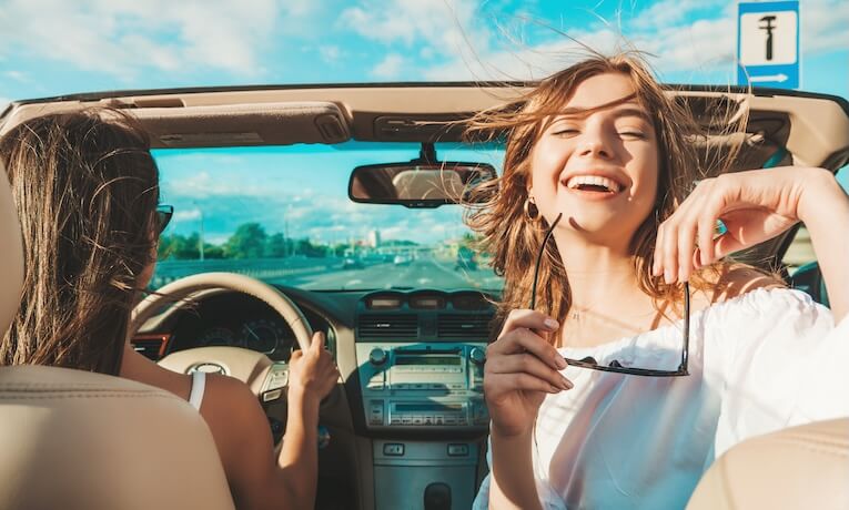 dvě mladé ženy jedou v kabrioletu