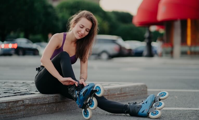 mladá žena si nazouvá inline brusle