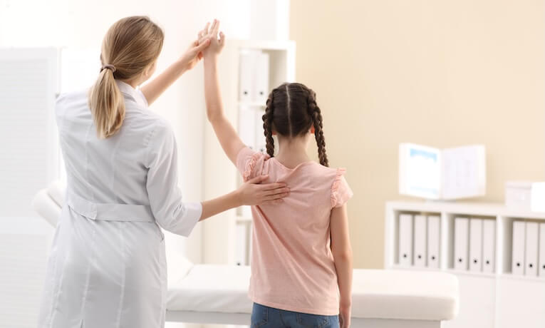 lékařka vyšetřuje dívce záda
