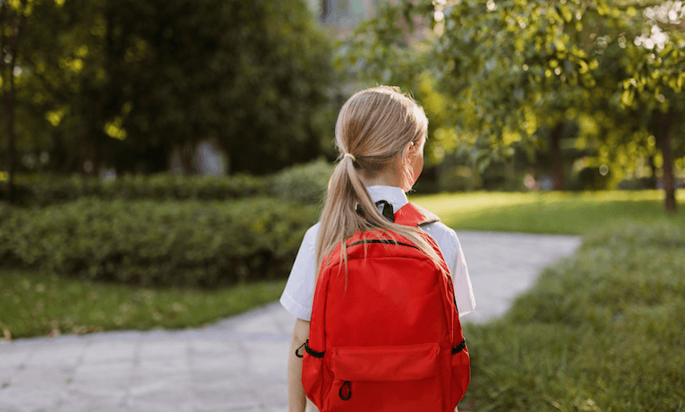 školačka s červenou školní taškou na zádech