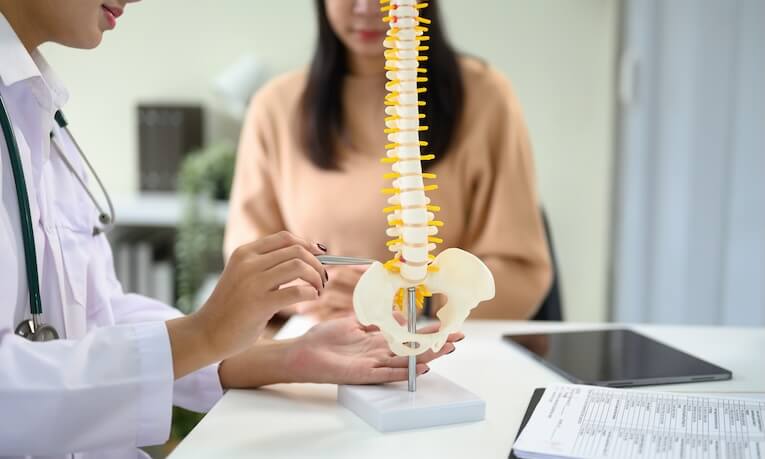lékařka pacientce vysvětluje pomocí modelu páteře