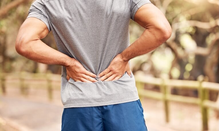 muž si drží bedra oběma rukama