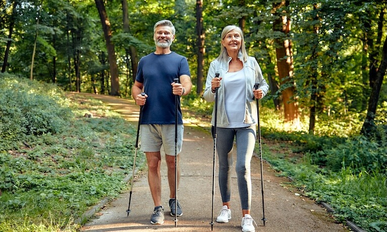 muž a žena středního věku na procházce s nordic walking