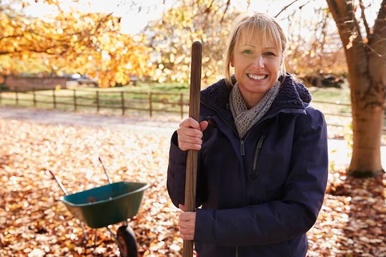 žena uklízí spadané listí na zahradě