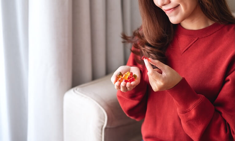 mladá žena drží v ruce hromádku gumových bonbónů