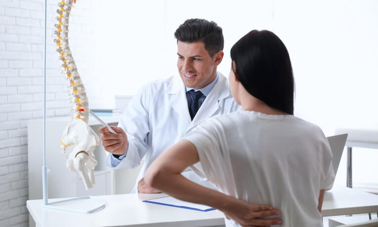 lékař pacientce vysvětluje pomocí modelu páteře