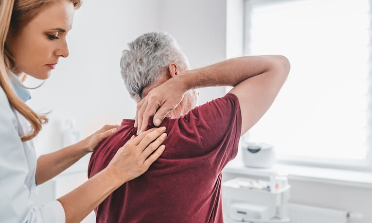 starší muž ukazuje lékařce, kde ho bolí záda