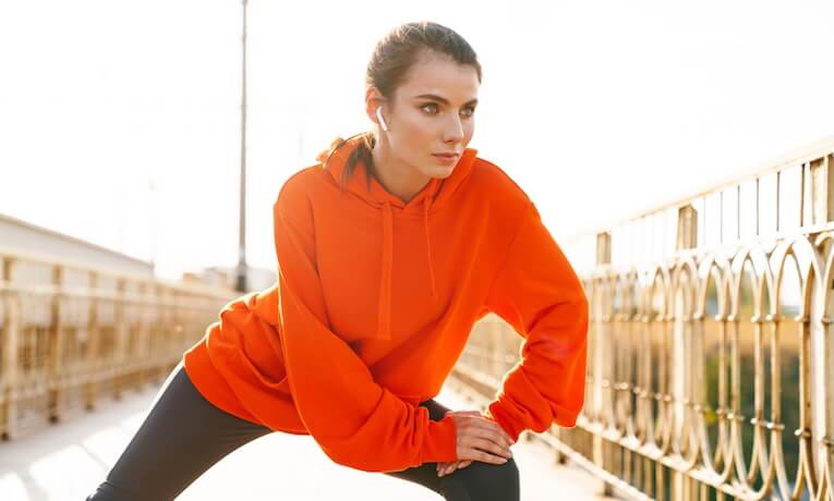 mladá žena v mikině a legínách se protahuje